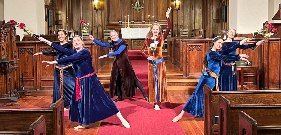 CreationDance - a group of six adults in long, velvety gowns dance inside a church while holding roses.
