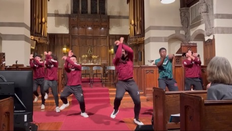 Six young adults, five wearing red, long-sleeved shirts and one wearing a green T-shirt, perform in the Sanctuary.