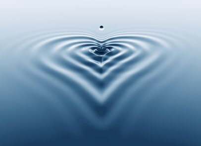 a drop of water enters a pool of ripples that form a heart shape