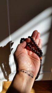 An outstretched hand holds wooden prayer beads.
