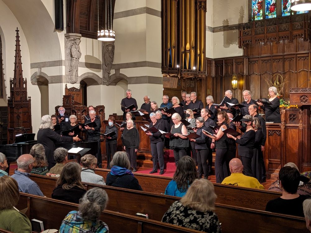 The FUUSN Choir sings in the sanctuary during the 175th Anniversary celebration, with audience members in the pews nearby.