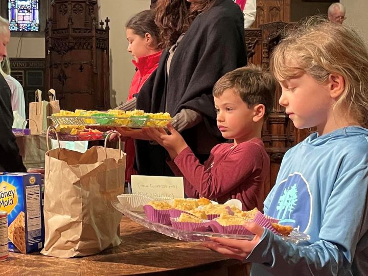 Children hold out trays of cornbread at the front of the Sanctuary.